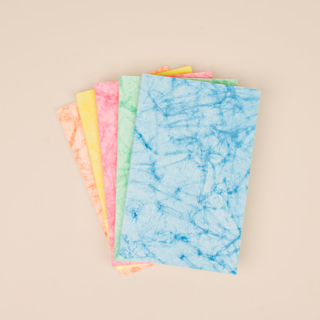 Stack of two handmade tie-dye pocket notebooks with colorful covers.